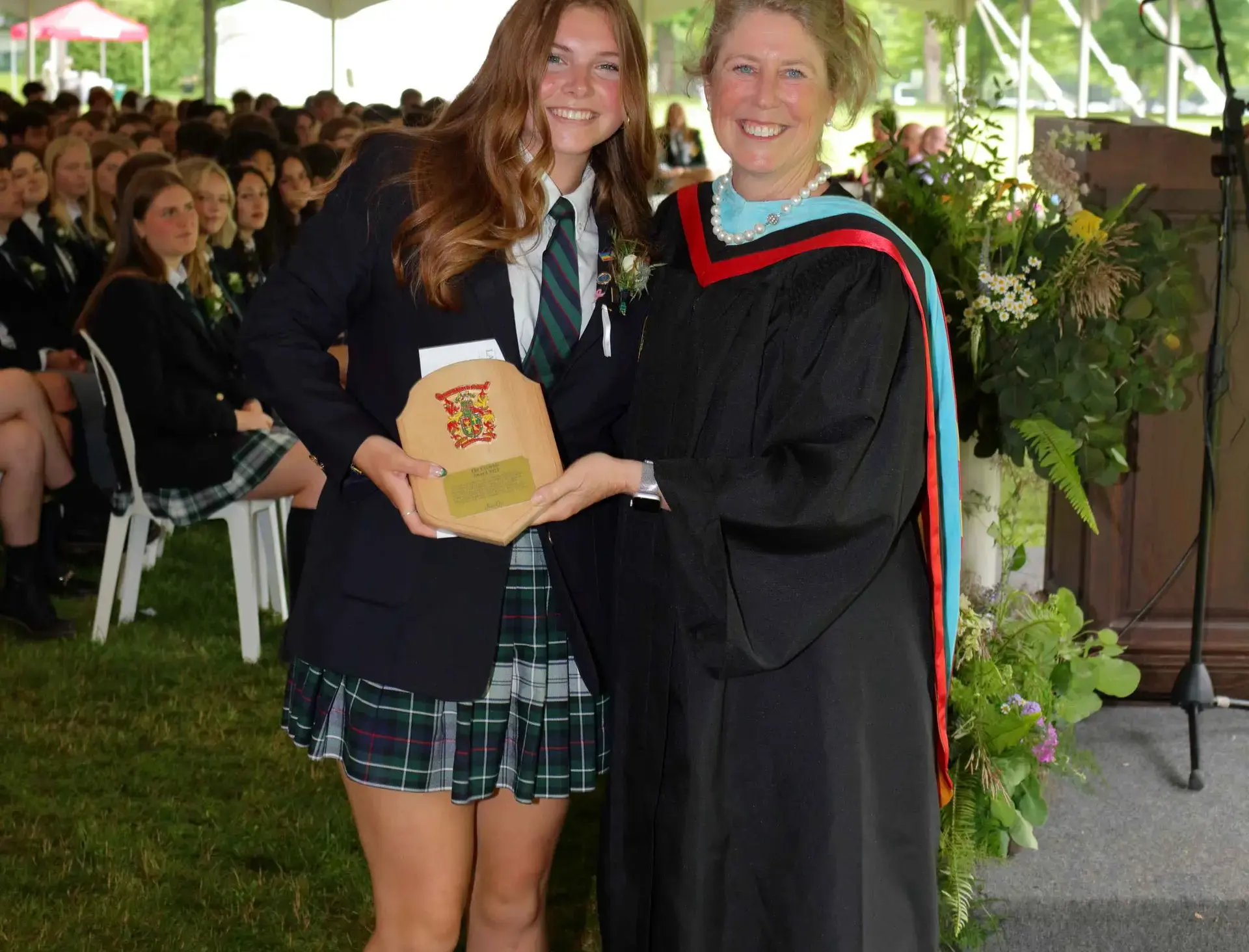 Two people standing together, one in graduation gown