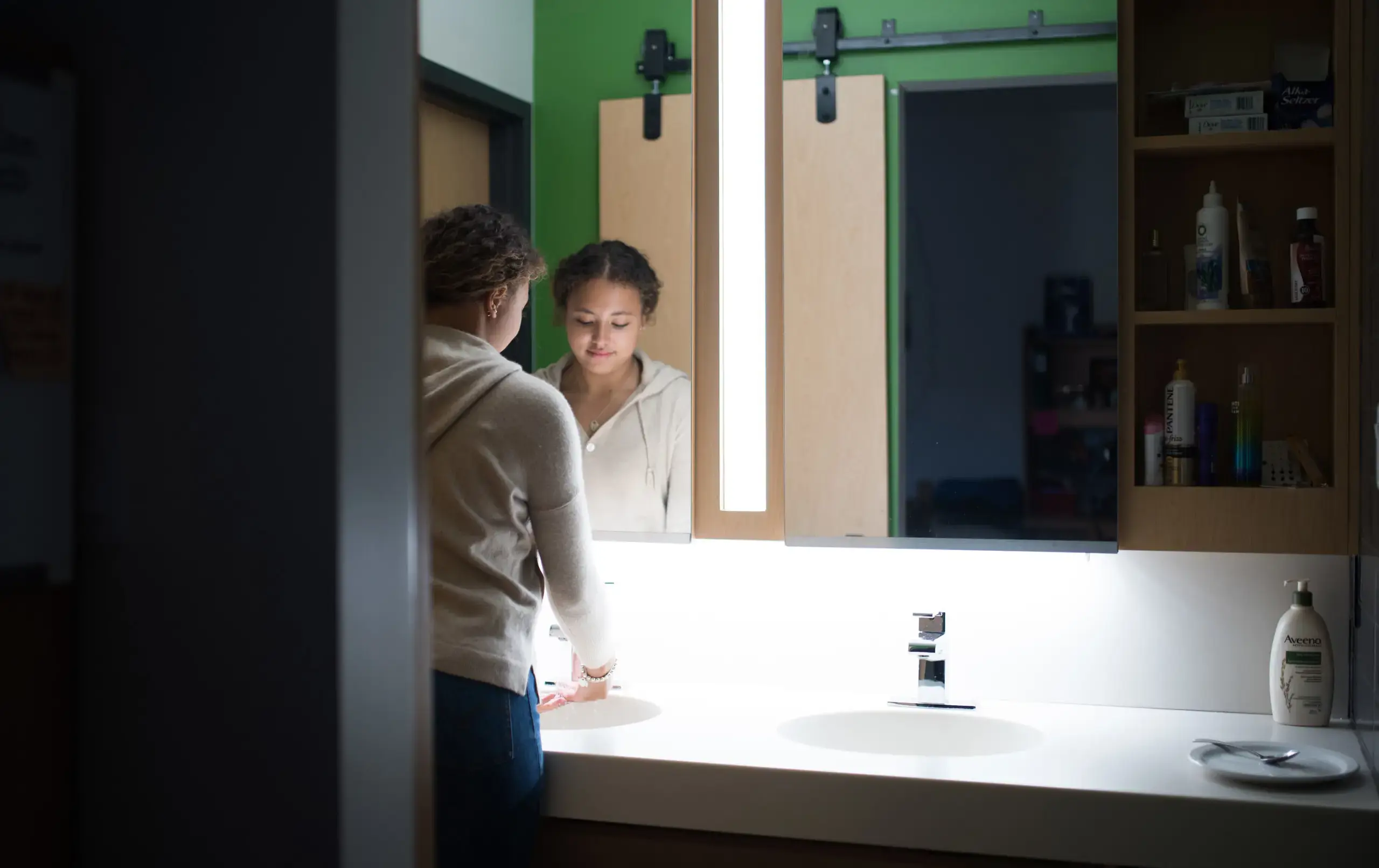 Student standing in front of bathroom mirror