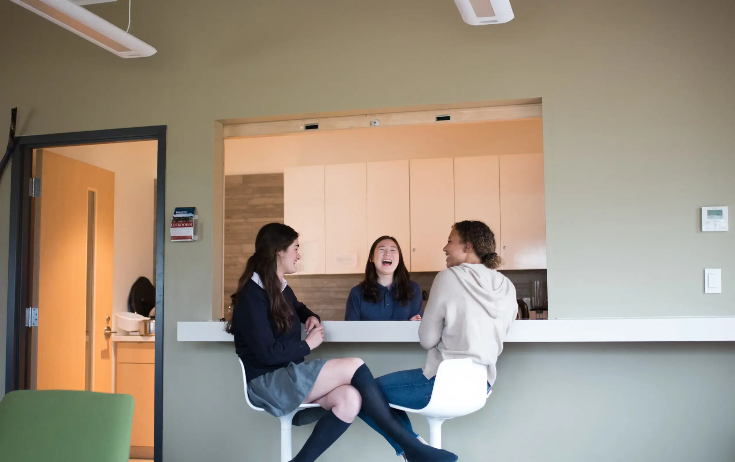 Three students laughing together in kitchen
