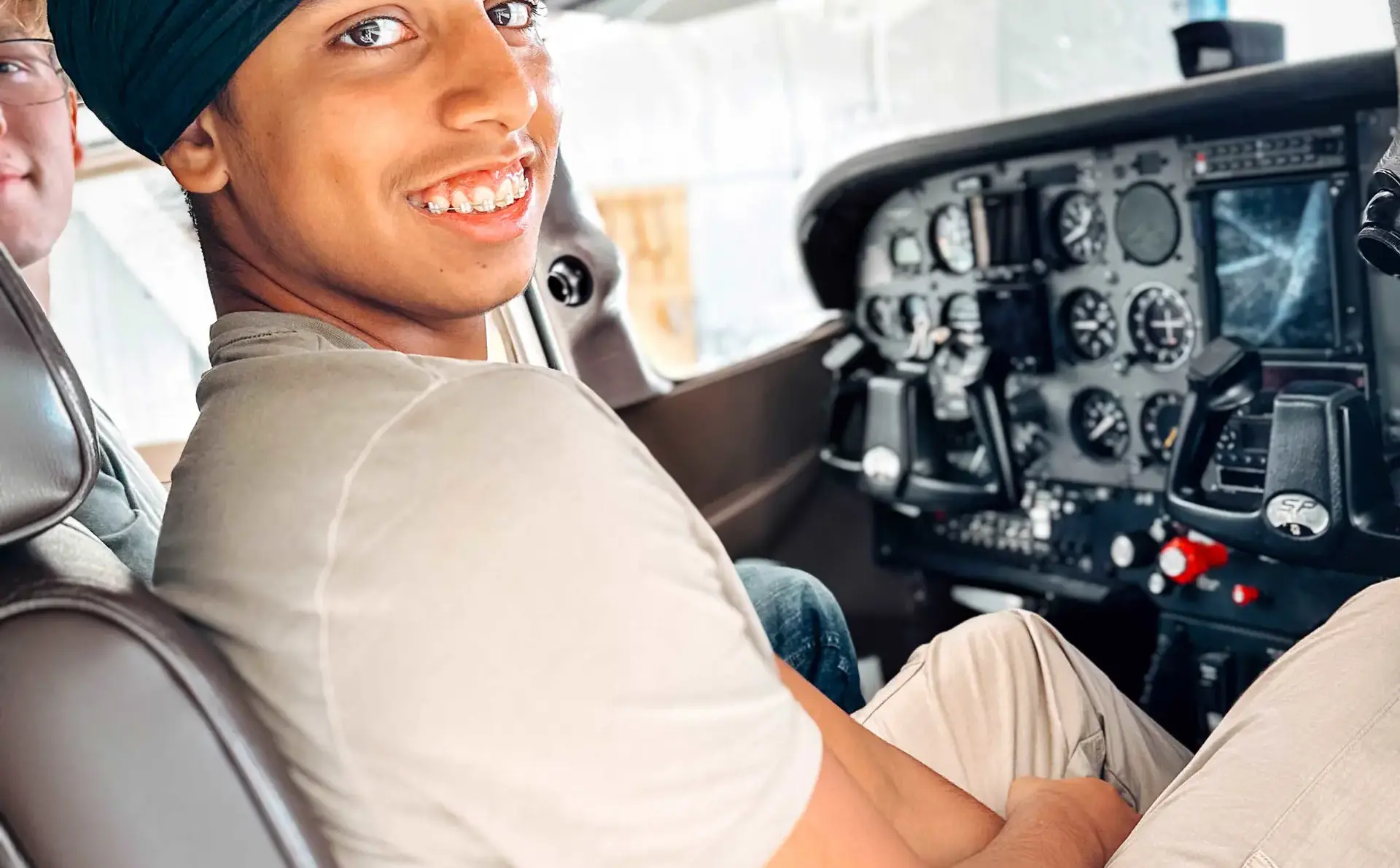 A smiling student sits in the cockpit of a small airplane.