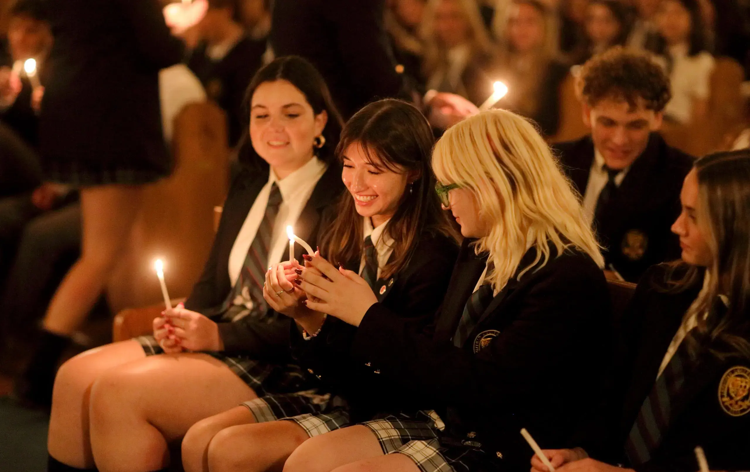 Smiling students holding candles