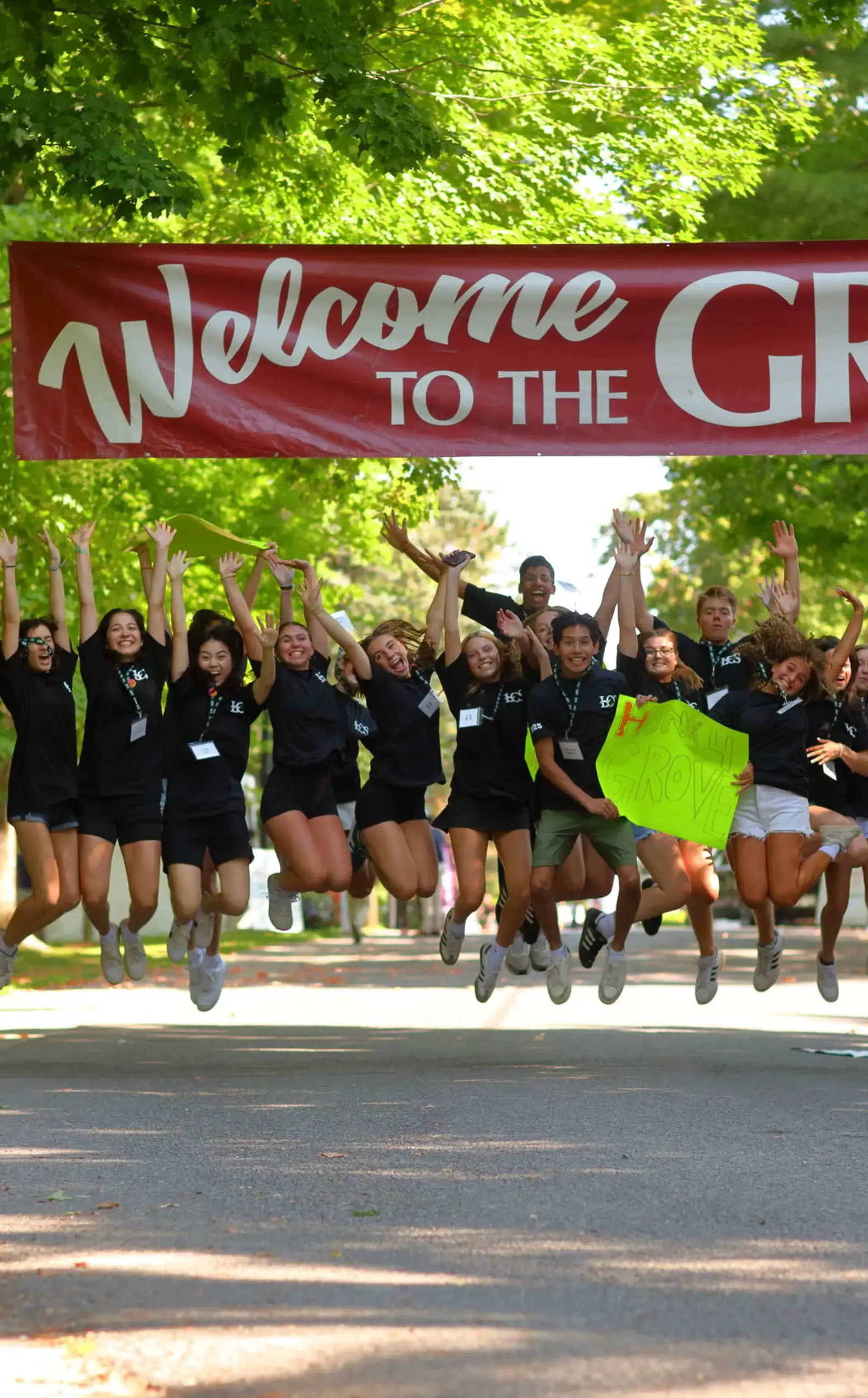 Students jumping in air, underneath Welcome to The Grove banner