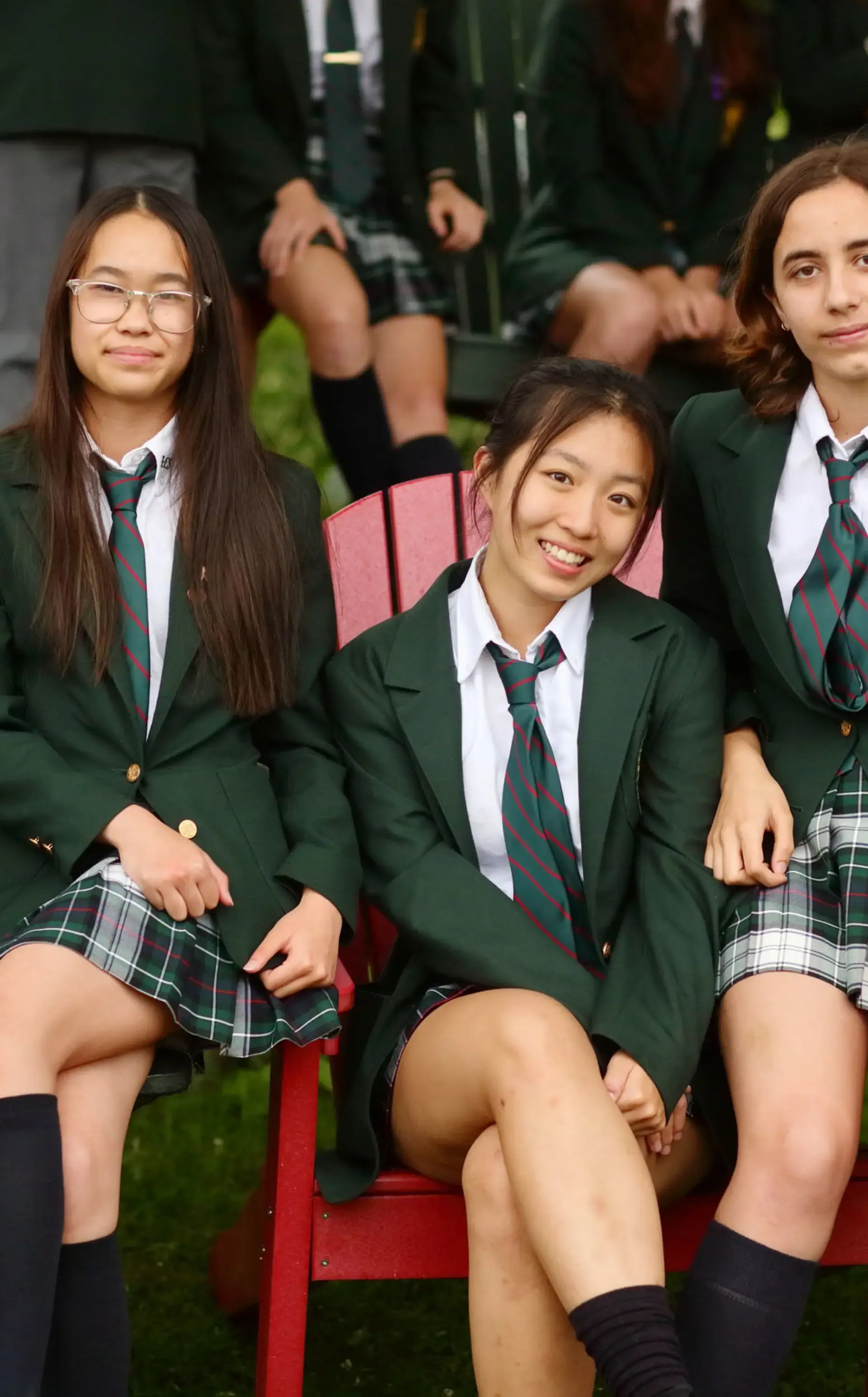 Students sitting on chairs outside, smiling