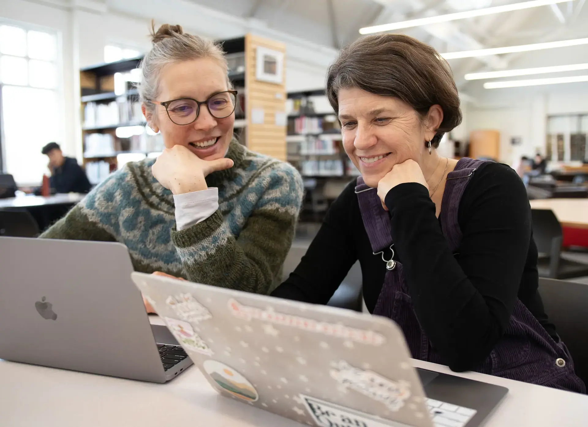 Two faculty member sitting at their laptops, smiling