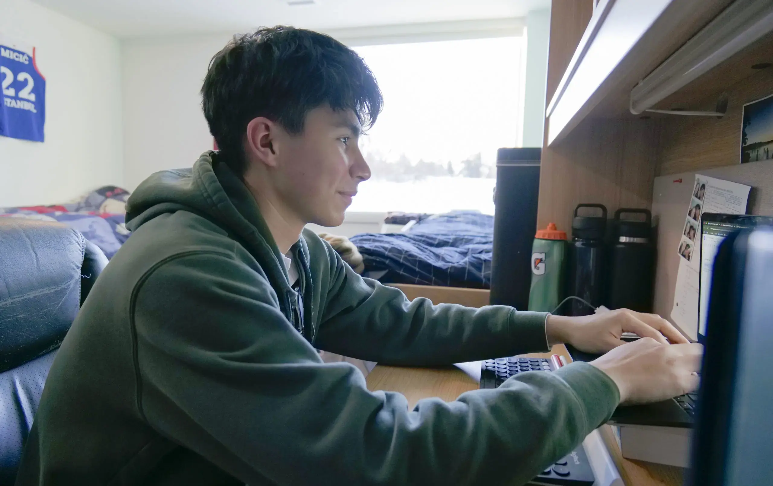 Student typing at computer in dorm room