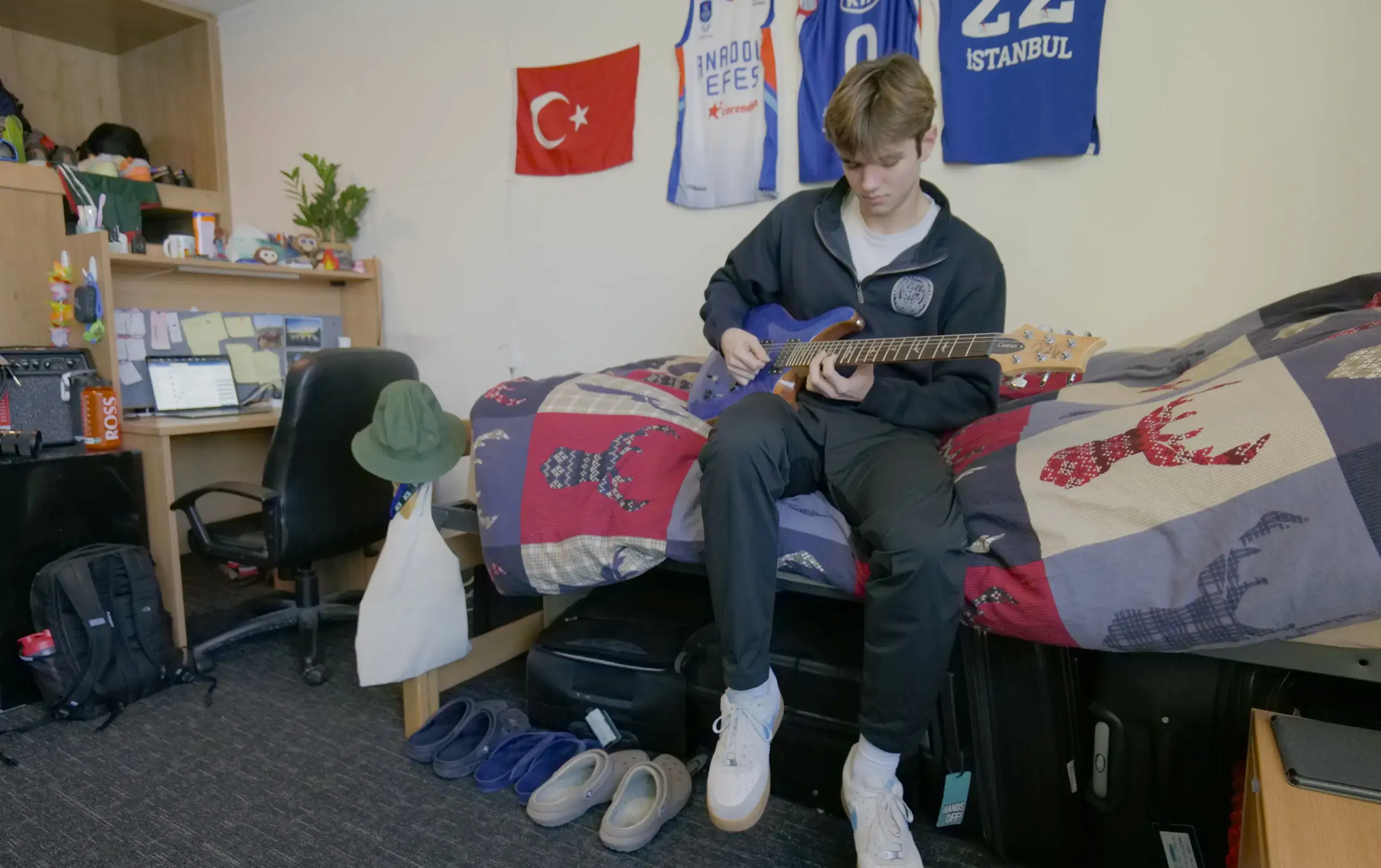 Student sitting on bed, playing guitar