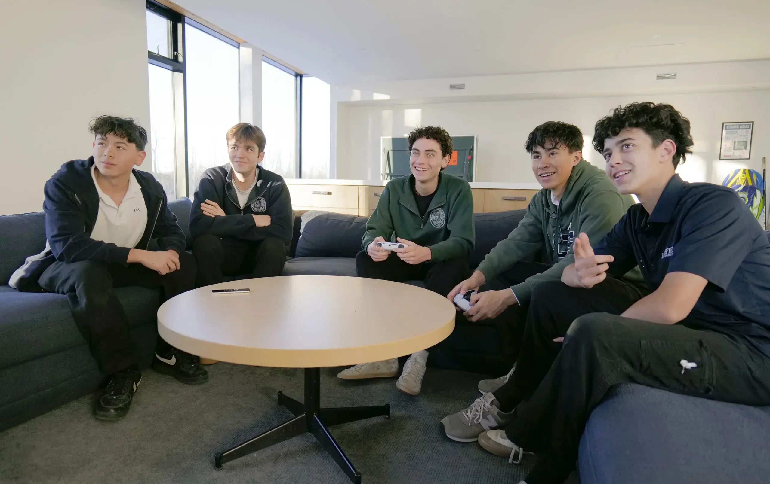 Students sitting around coffee table, looking at something out of shot