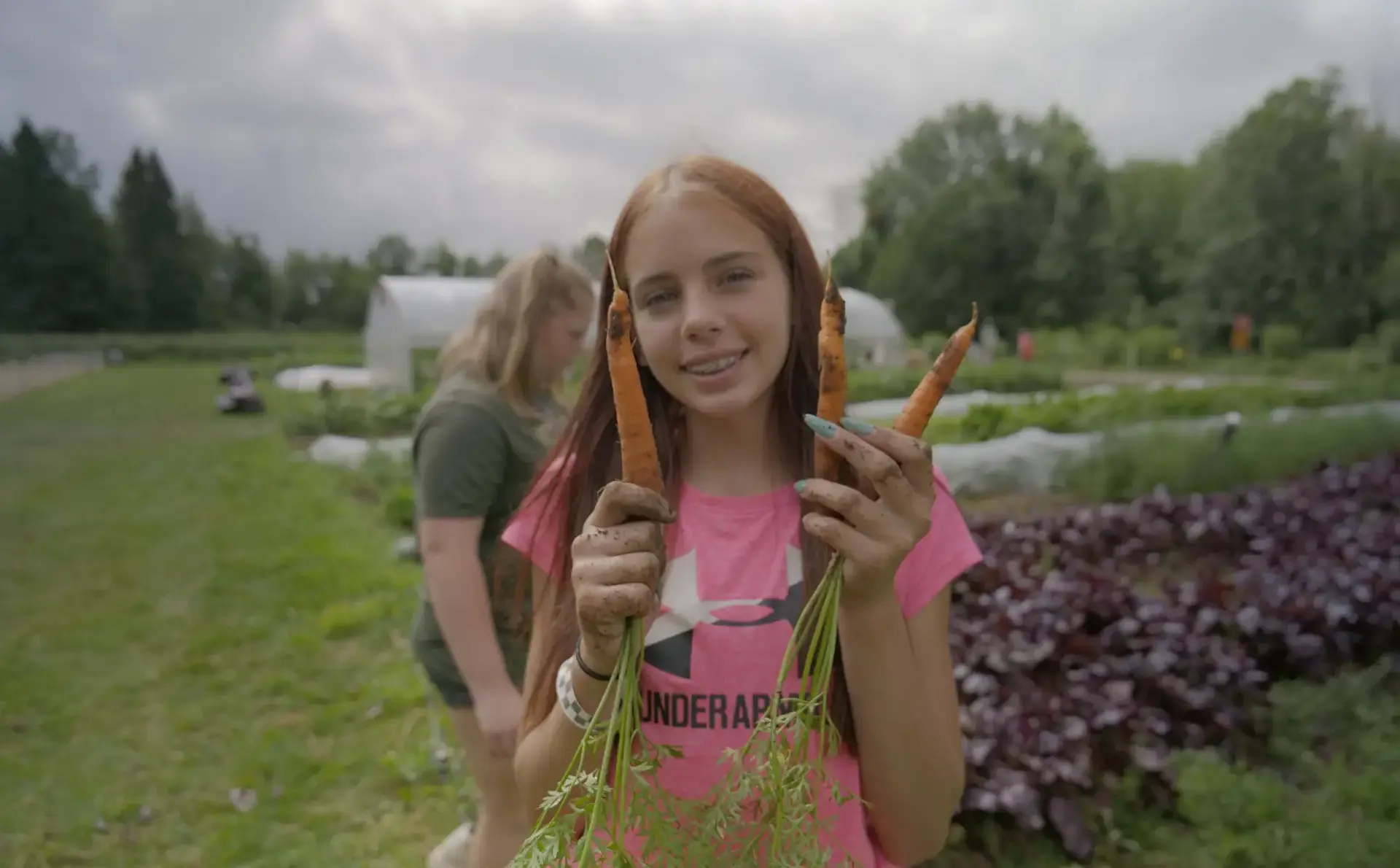Camper holding up carrots while smiling at Northcote Campus during LCS Camps